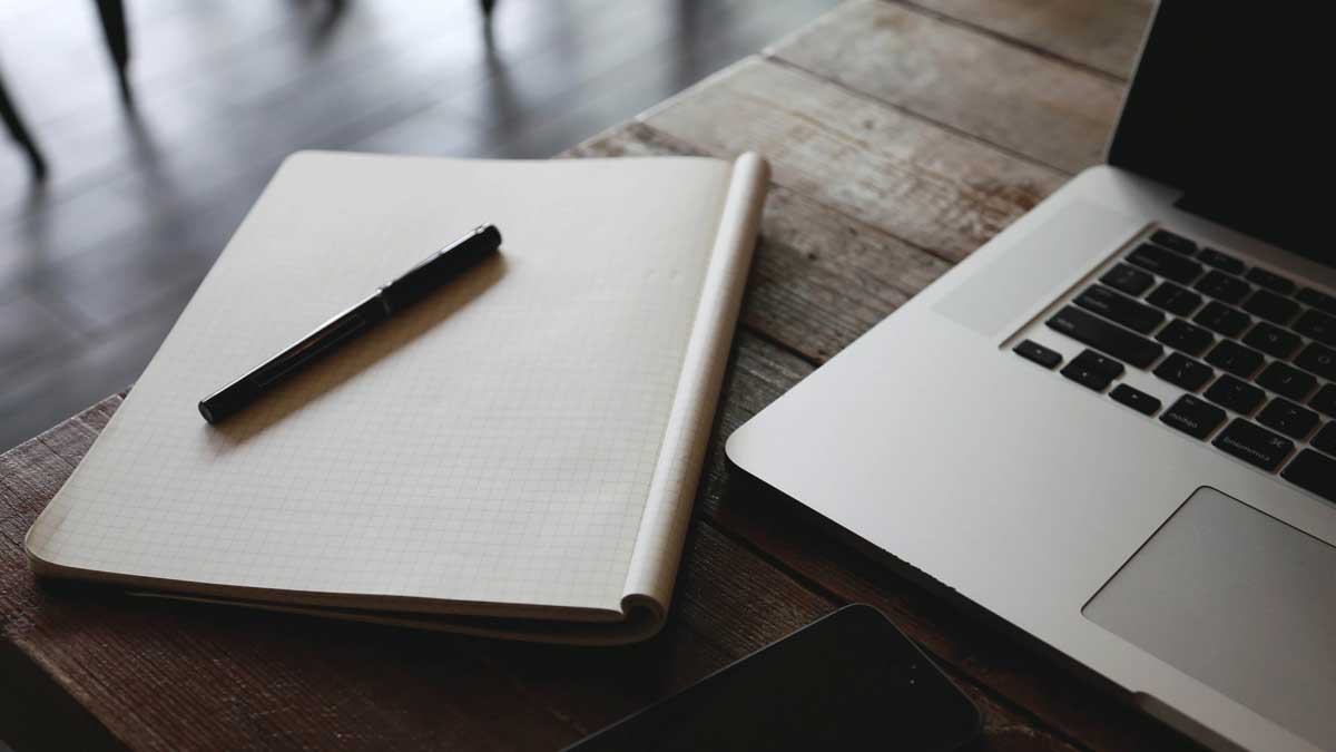 Desk with pen and notebook and open laptop